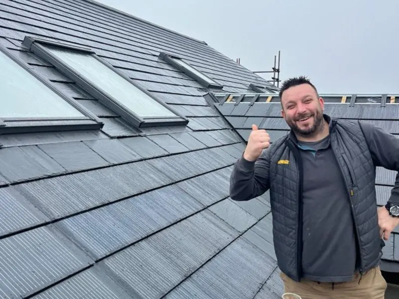 A man beside solar tiles and rooflights during installation