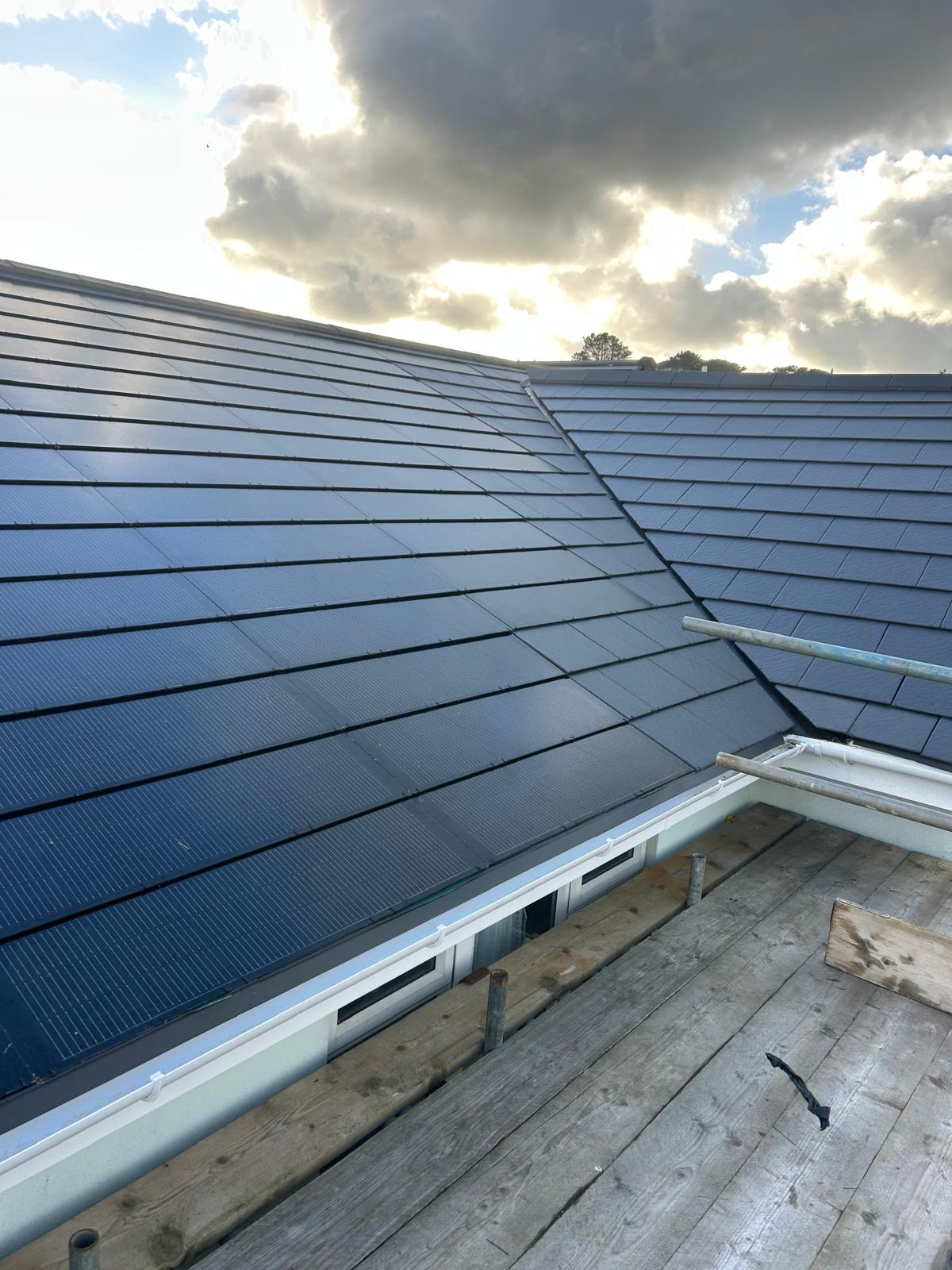 Solar tiles on a Guernsey HMO. Roof-integrated solar tiles across adjoining slopes, photographed during the installation.